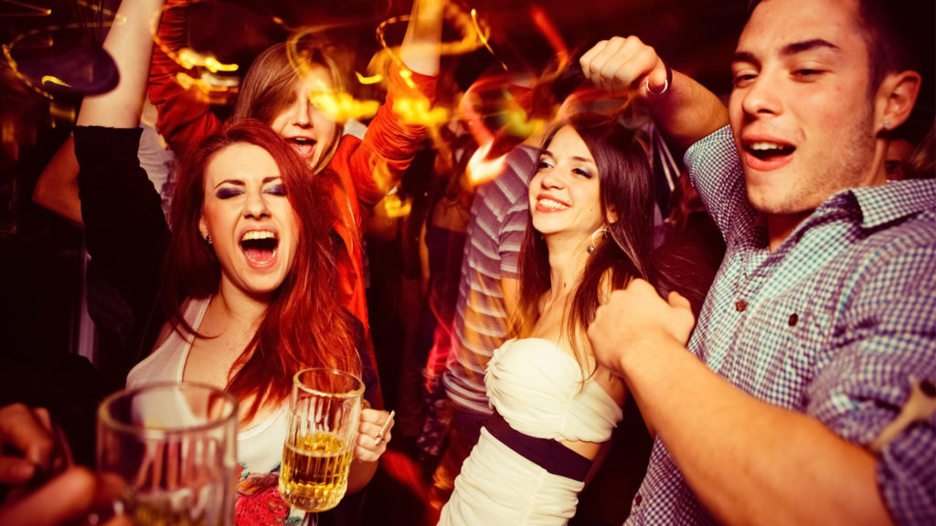 Group of friends enjoying a lively night out with drinks and dancing.