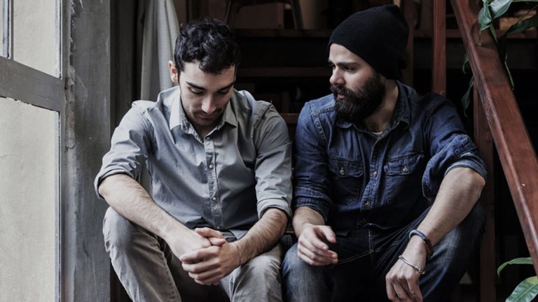 Two men sitting closely, engaged in a serious conversation.