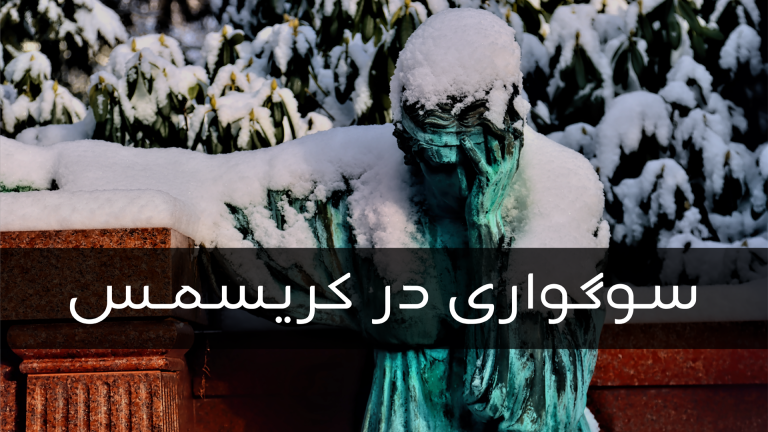 A snow-covered statue with hands on face in a wintry setting.