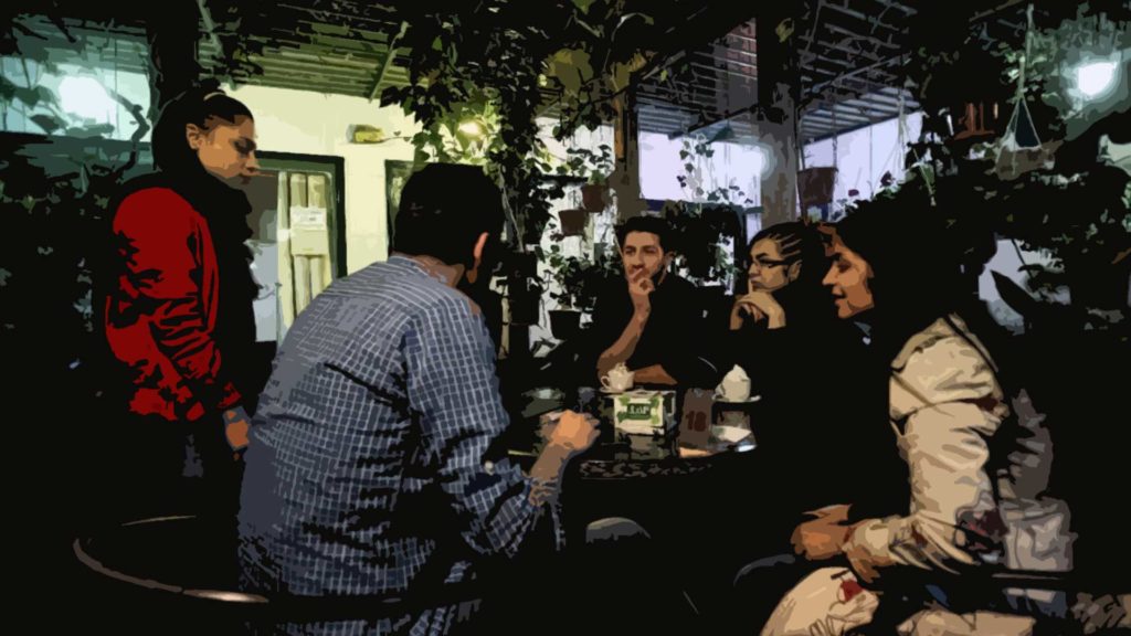 Group of friends enjoying drinks and conversation at a cozy outdoor cafe.