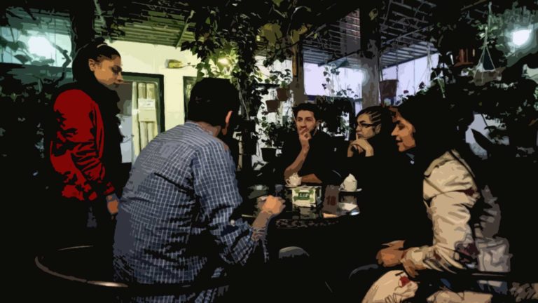 Group of friends enjoying drinks and conversation at a cozy outdoor cafe.