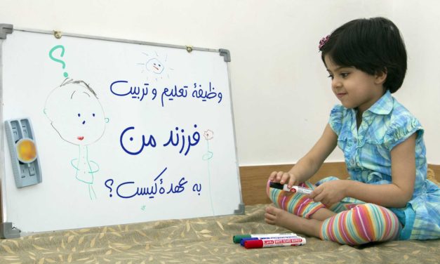 A child playing with toys beside a whiteboard with Persian writing.