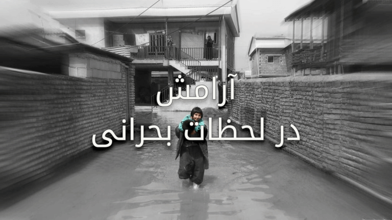 A person wades through floodwaters in a residential area.