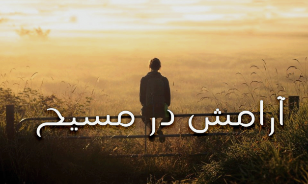 شخصی ایستاده در مسیر روستایی هنگام طلوع خورشید.