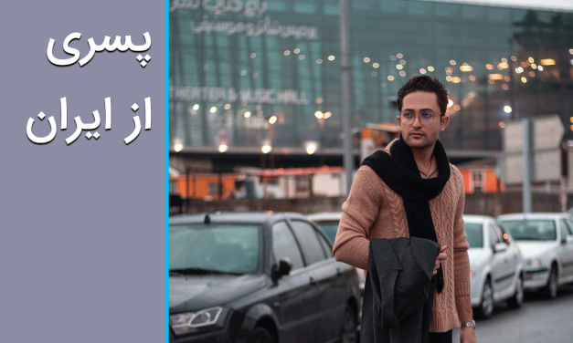 A young man standing beside parked cars in an urban setting with text in Persian.
