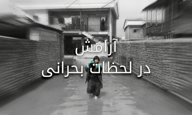 Flooded street with a person wading through water in front of houses.