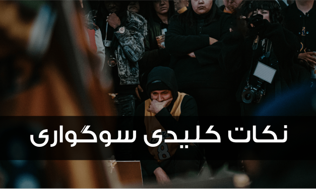 A person in a dark hoodie and mask amidst a crowd, with Arabic text overlay.